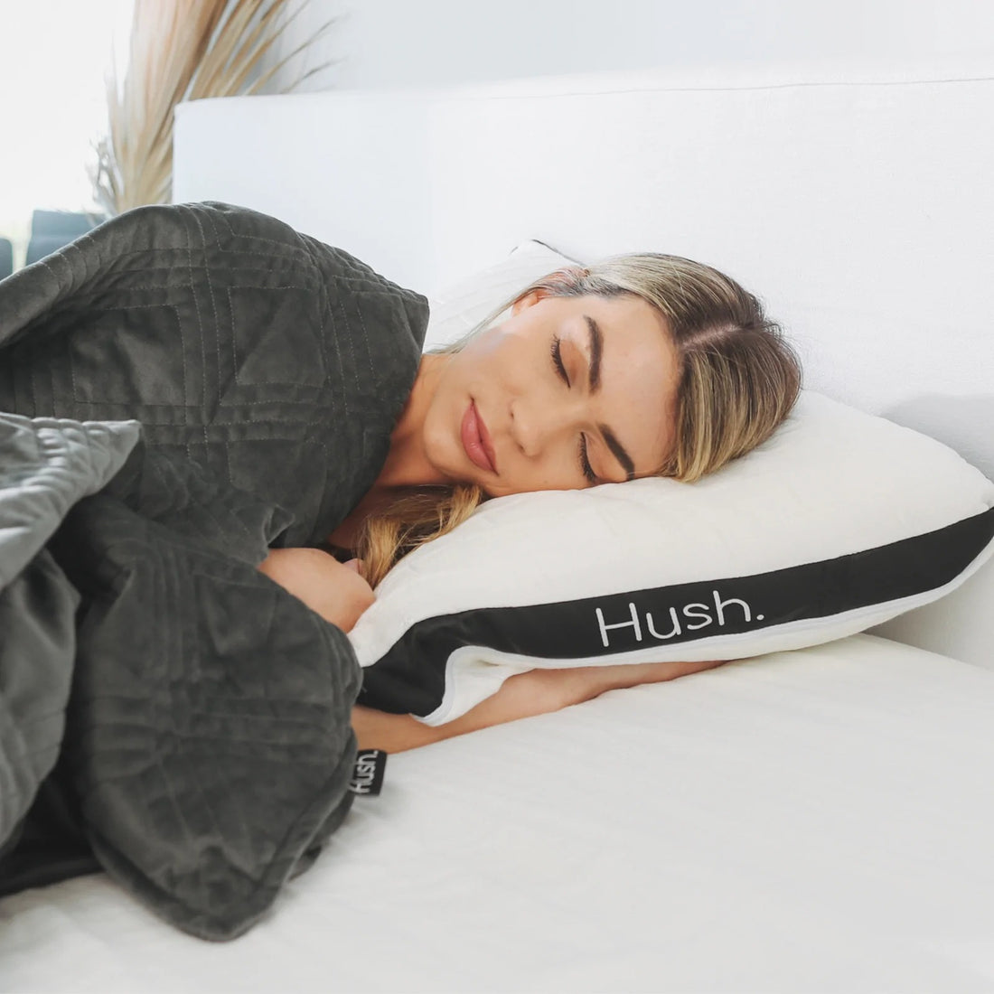 A young woman sleeps on a Hush pillow.