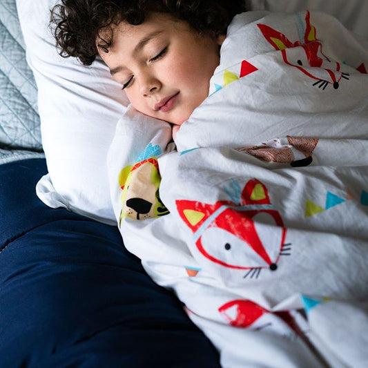 Little boy sleeping peacefully on the bed wraped in Hush weighted blanket for sensory issues