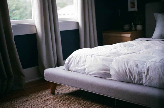 a bed with white colored duvet